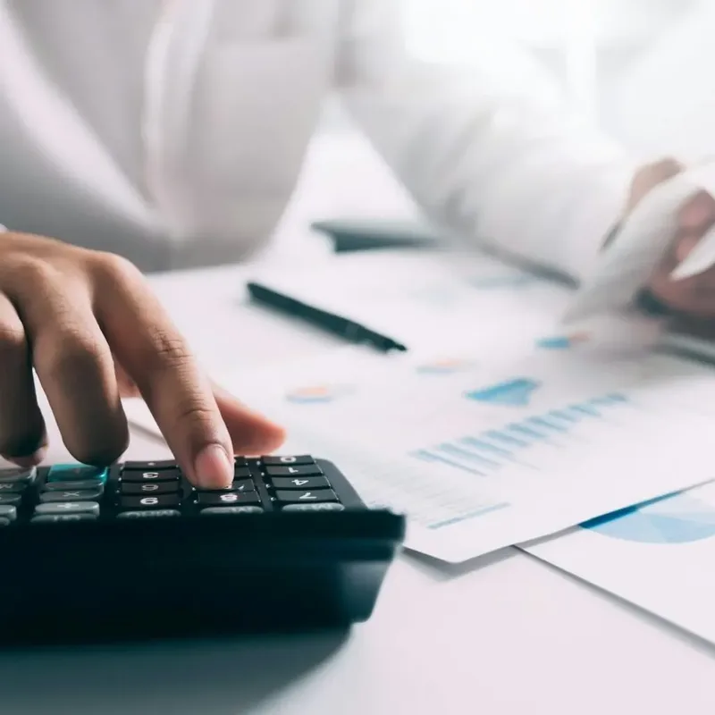 Businessperson punching figures into a calculator beside financial reports – Zidika Consulting, Kenya