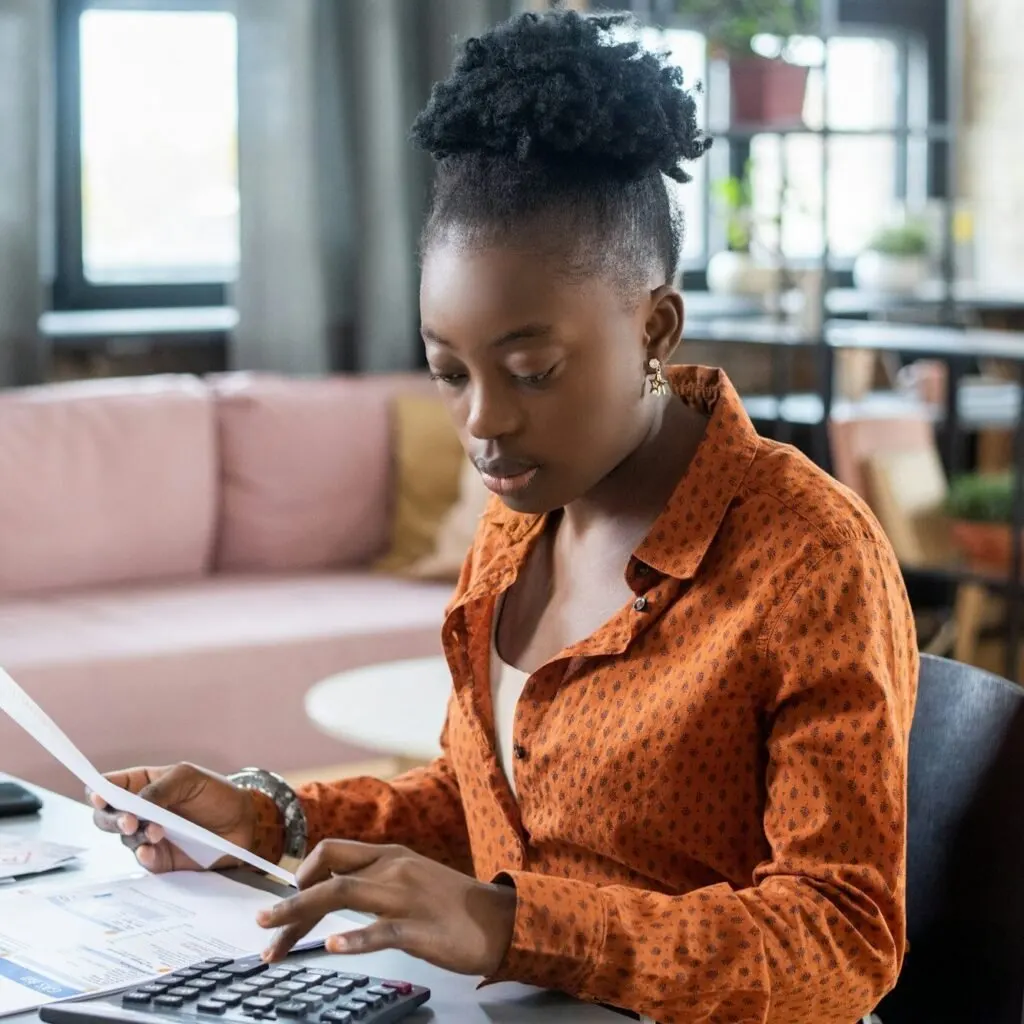 Young woman calculating withholding tax in Kenya using a paper and calculator – Zidika Consulting